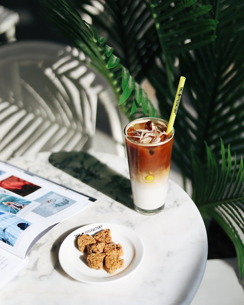 Refreshing iced coffee with cookies on a marble table, perfect indoor cafe setting.