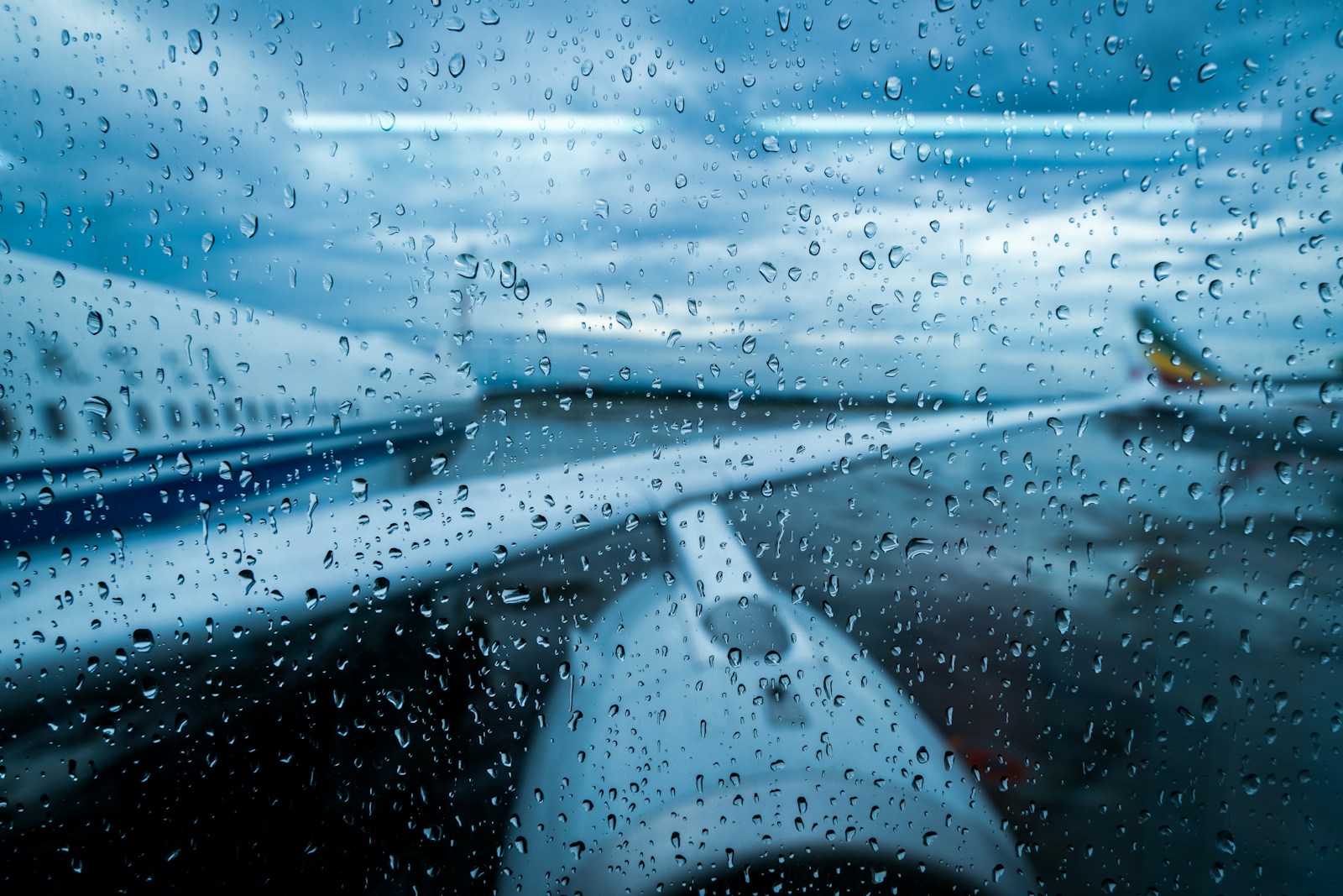 Airplane wing through raindrops on window