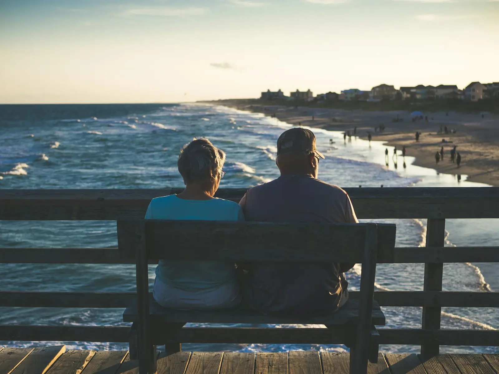 man and woman sitting on bench in front of beach while thinking about annuities